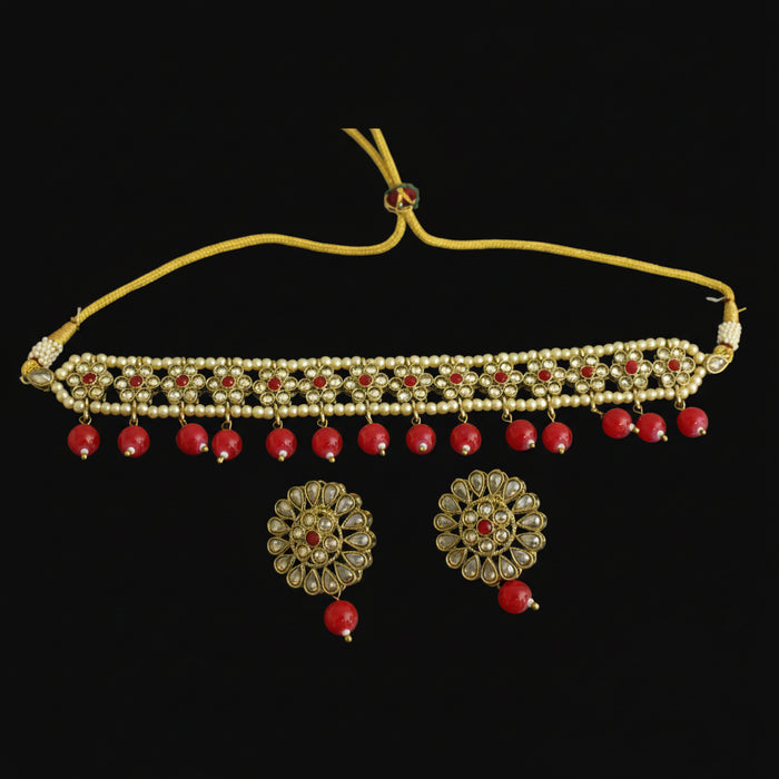 Gold necklace with red stones and matching earrings on a dark background