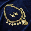 Gold necklace with coin pendants and matching earrings on a dark background