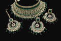 Ornate jewelry set with green and gold accents on a dark background