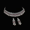 Jewelry set with necklace and earrings on a dark background, featuring the brand 'Saheli'.