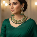 Woman wearing traditional green jewelry against a dark background