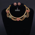 Gold necklace with floral designs and matching earrings on a black stand with 'SAHELI' branding.