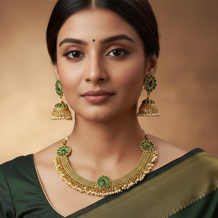 Gold and green jewelry set on a black stand with 'Saheli' branding.