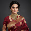 Gold necklace with red beads and matching earrings on a black background