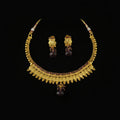 Gold-toned traditional necklace and matching earrings with dark purple teardrop stones, displayed on a dark reflective surface. The SAHELI MY BEST FRIEND logo is visible in the top left corner.