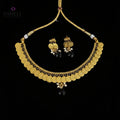 Gold coin necklace and matching earrings with black beads and white pearl accents, displayed on a dark reflective surface. The SAHeli by Saheli brand logo is visible in the top left corner.