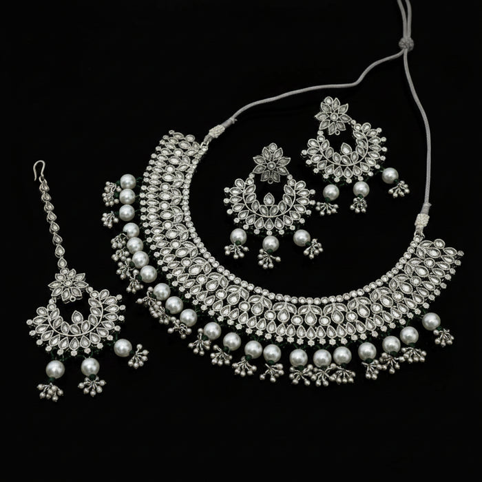 Silver jewelry set including necklace, earrings, and tikka on a dark background