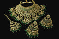 Gold and green jewelry set on a dark background