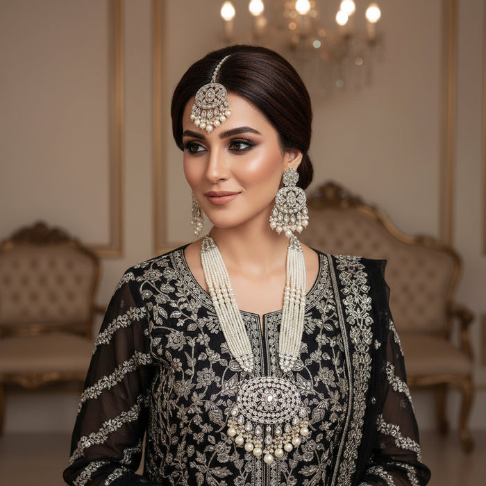 Silver jewelry set with necklaces and earrings on a reflective surface