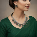 Necklace with floral silver pendants and green stones on a gray background