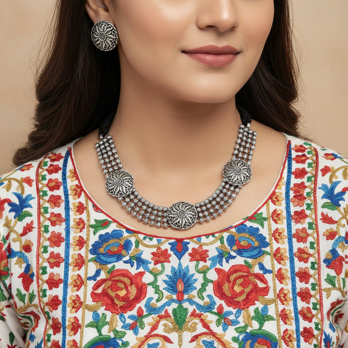 Silver necklace and earrings set on a reflective surface