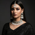 Silver jewelry set including a tiara, earrings, and necklace on a dark background with 'SAHELI' branding.