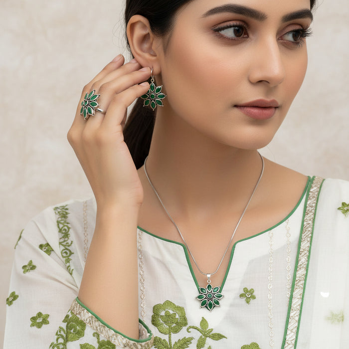 Silver jewelry set with green floral designs on a gray background