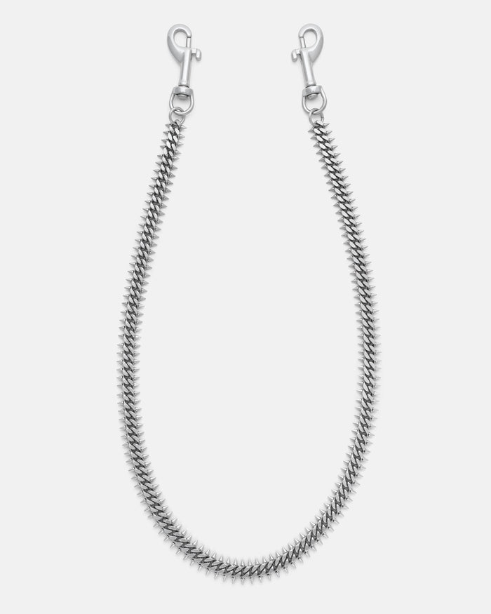 Silver spiked Cuban wallet chain with 2mm spikes on either side for a brutalist feel. Silver heavy duty hardware clips to hook onto you belt loops. on grey background.