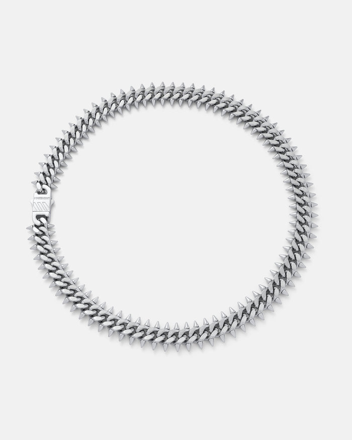 The "Screwed Up" Spiked Cuban Chain is a silver necklace with closely arranged pointed spikes in a circular pattern, shown against a plain white background.