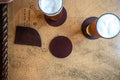 Burgundy leather coasters with cork backing on a nautical chart table with two beers