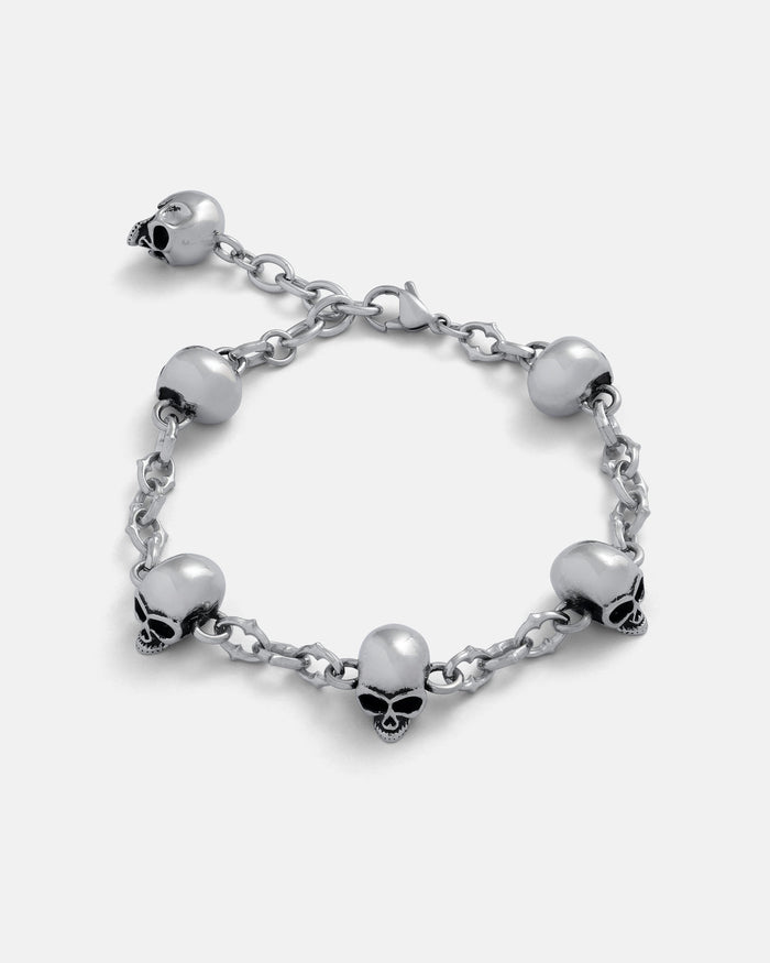 Silver 6mm Cathedral chain bracelet with skull charms around and a 2.5cm Extender by statement collective on grey background.