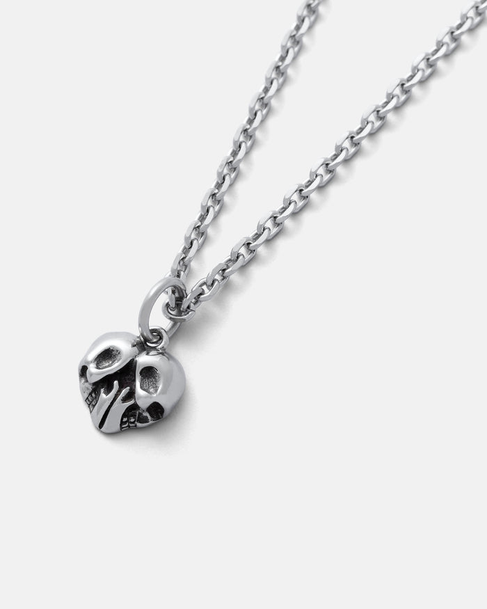 The Skull Heart Pendant is a silver-tone stainless steel necklace with a detailed skull heart charm, displayed on a light gray background—ideal for fans of dark romance jewelry.