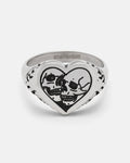 The STATEMENT Skull Heart Ring is a silver heart-shaped ring showcasing two black skulls facing each other engraved on the front, accented with subtle decorative markings along the sides. This bold piece of gothic jewelry is perfect for those who embrace unique and unconventional style.