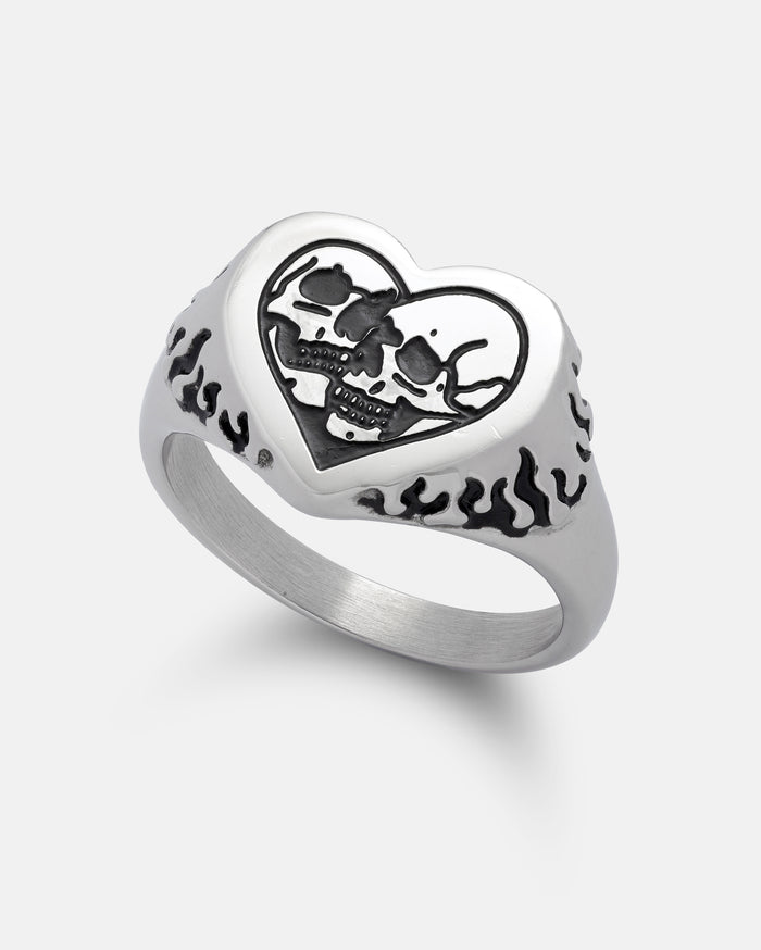 The STATEMENT Skull Heart Ring features a heart-shaped face with two skulls set inside, while the band is adorned on both sides with an intricate black flame design. This bold piece of gothic jewelry brings an edgy flair to your collection.