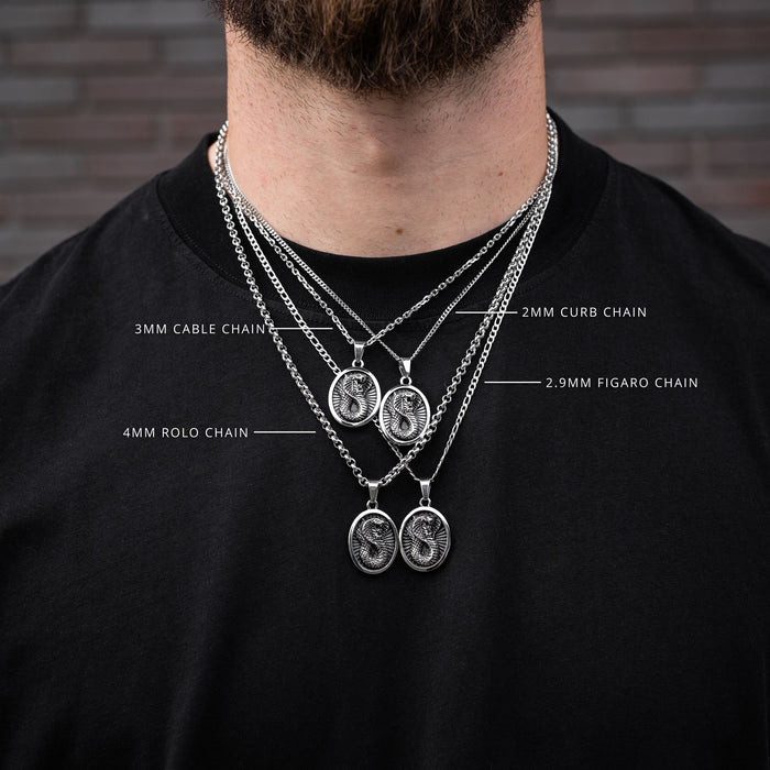 Man wearing multiple silver cobra pendant chains with labeled chain types against a brick wall background.