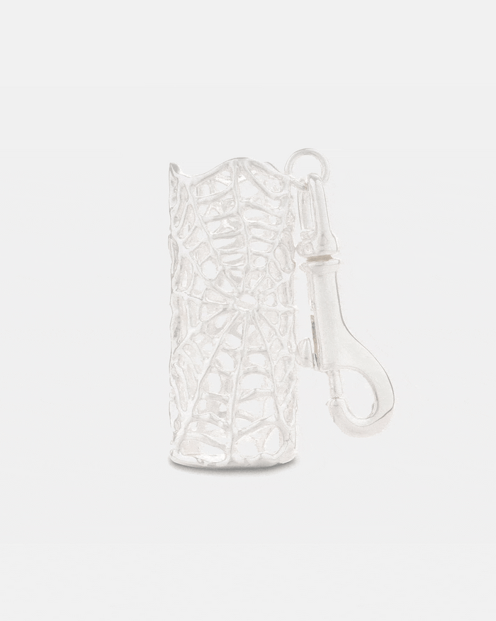 A silver Spiderweb Lighter Sleeve by Statement Collective, shaped like a cylindrical leaf skeleton with intricate vein patterns and an attached clasp for securing keys.