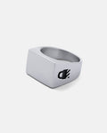 The Statement Signet Ring is a silver stainless steel signet ring with a polished finish and a small black engraved paw print design on one side, shown against a plain light gray background.
