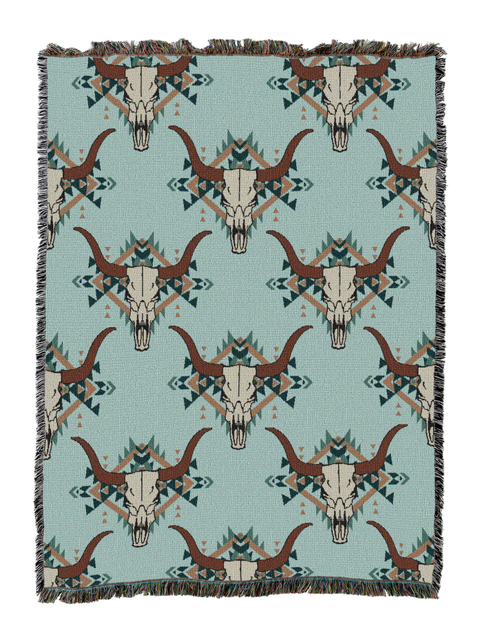 Steer skull cotton throw in the Fiesta colorway, repeating longhorn skulls with rust horns and teal accents on a soft sage blue ground