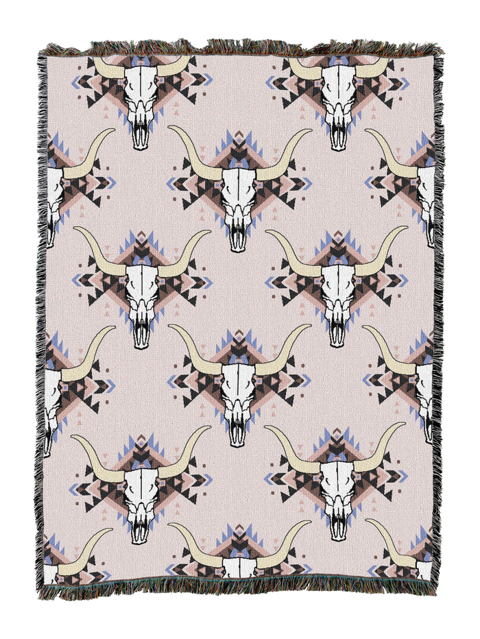 Steer skull cotton throw in the Cream colorway, repeating longhorn skulls in grey and tan with lavender accents on a pale pink white ground