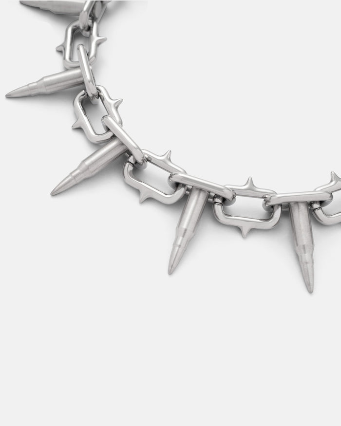 A close-up of the Statement Collective "Sweating Bullets" Necklace Chain: a 12mm heavy-duty stainless steel design with bullet-shaped pendants and spiked metal links, displayed on a plain white background.