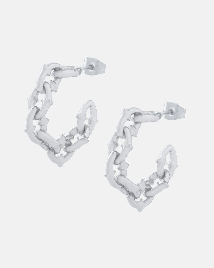 The Cathedral" Hoop Earrings feature gothic-inspired, interconnected bone-like hoops with a spiked chain link texture and jagged design. These statement earrings fasten with stud posts for a bold, edgy look.
