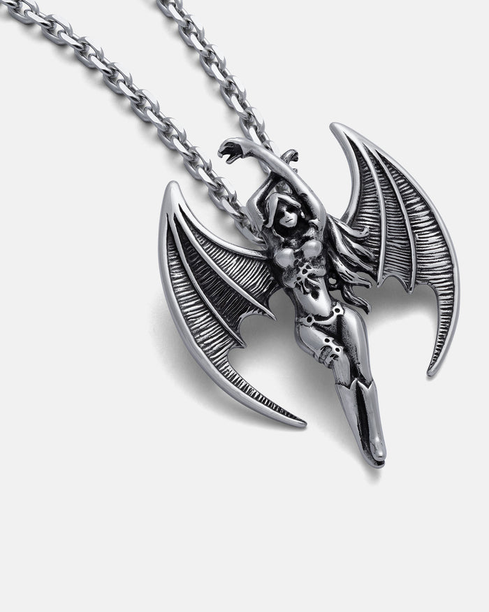 The Enchantress" Pendant is a silver hand-carved necklace with a succubus design, featuring detailed bat-like wings and an intricate body, displayed on a textured chain against a white background.