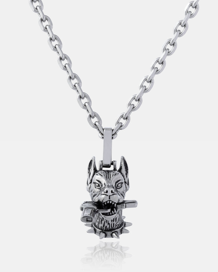 The Guard Dog" Pendant is a silver chain necklace with a detailed wolf’s head holding a small hammer and accented by a spiked collar—ideal for fans of bold hip hop jewelry.