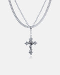 The Ruins" 6mm Set features a layered stainless steel necklace with a gothic cross pendant on the shorter chain and a Cuban link chain, all showcased against a plain white background.