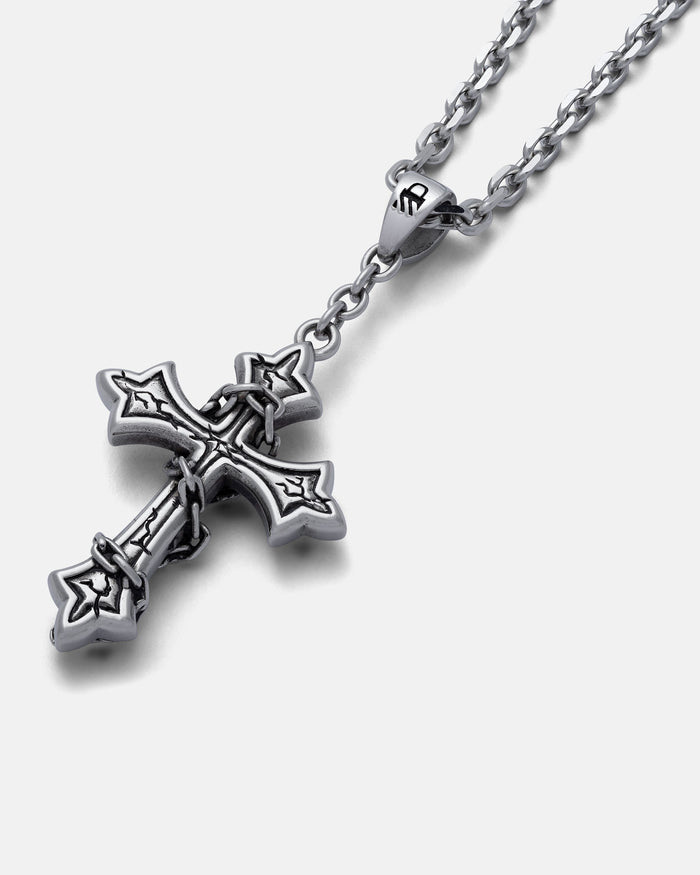 The Ruins" Pendant is a silver chain wrap jewelry piece with a gothic cross pendant featuring pointed edges and decorative details, displayed on a white background.