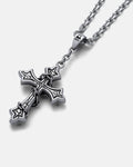 The Ruins" Pendant is a silver chain wrap jewelry piece with a gothic cross pendant featuring pointed edges and decorative details, displayed on a white background.
