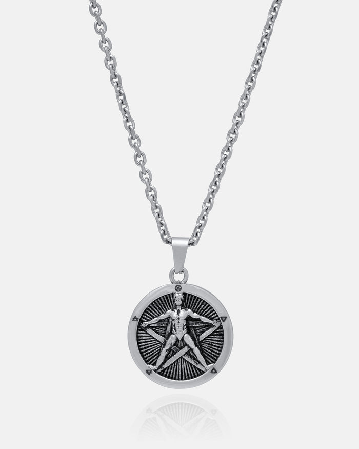 Introducing "The Star of the Magi" Pendant: a durable stainless steel necklace with a silver chain and a round pendant engraved with a Vitruvian Man-like figure against a radiant sunburst background.