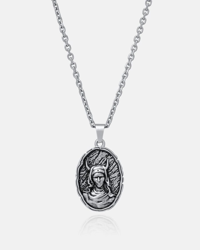 The Unholy" Pendant is a silver gothic necklace with an oval pendant engraved in relief with a helmeted figure on a textured background, crafted from durable 316L stainless steel for lasting shine and strength.